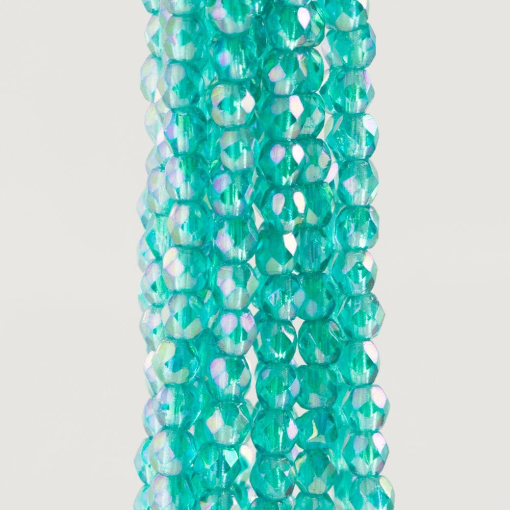 Turquoise glass beads with iridescent finish on a white background