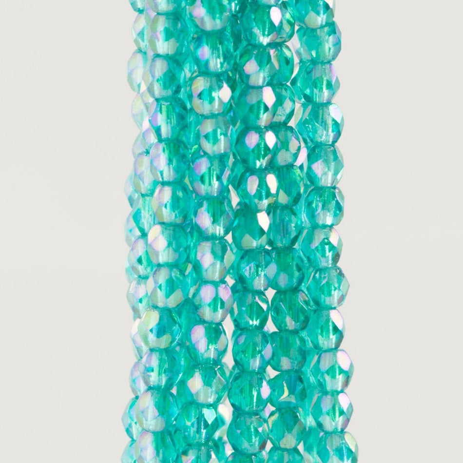 Turquoise glass beads with iridescent finish on a white background